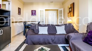 Ein Wohnzimmer mit einer Couch, einem Couchtisch und einem Schrank. Eine Tür und ein Gemälde sind an der Wand zu sehen.