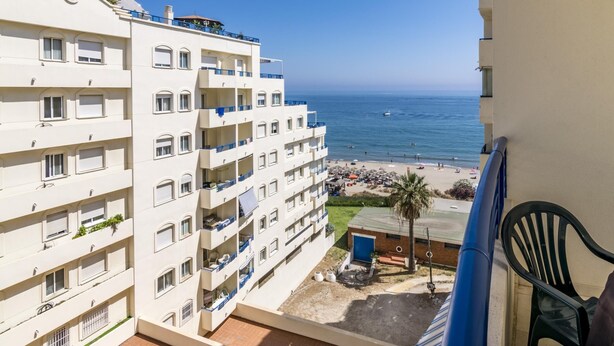 A multi-story hotel with balconies overlooking a beach.