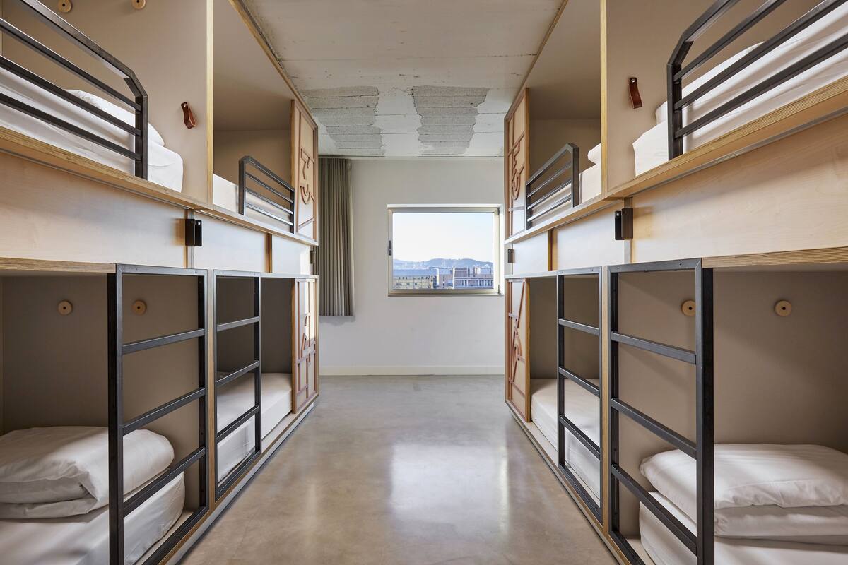A corridor with bunk beds, a window with a view, and a door at the end.