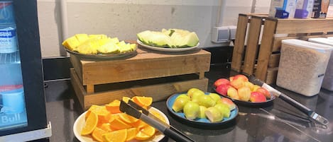 A buffet table with various fruits and a yogurt dispenser.