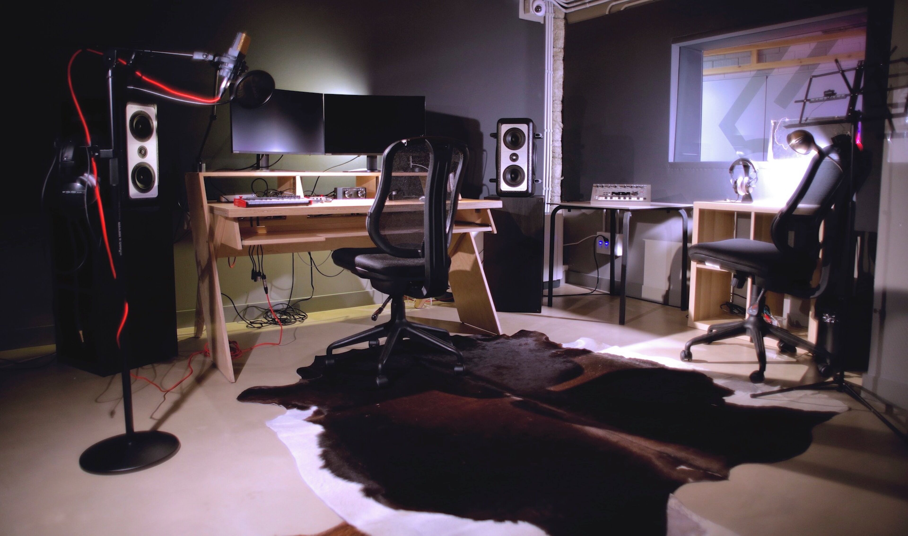A home office with a desk, two chairs, a computer, a large monitor, and a speaker system.