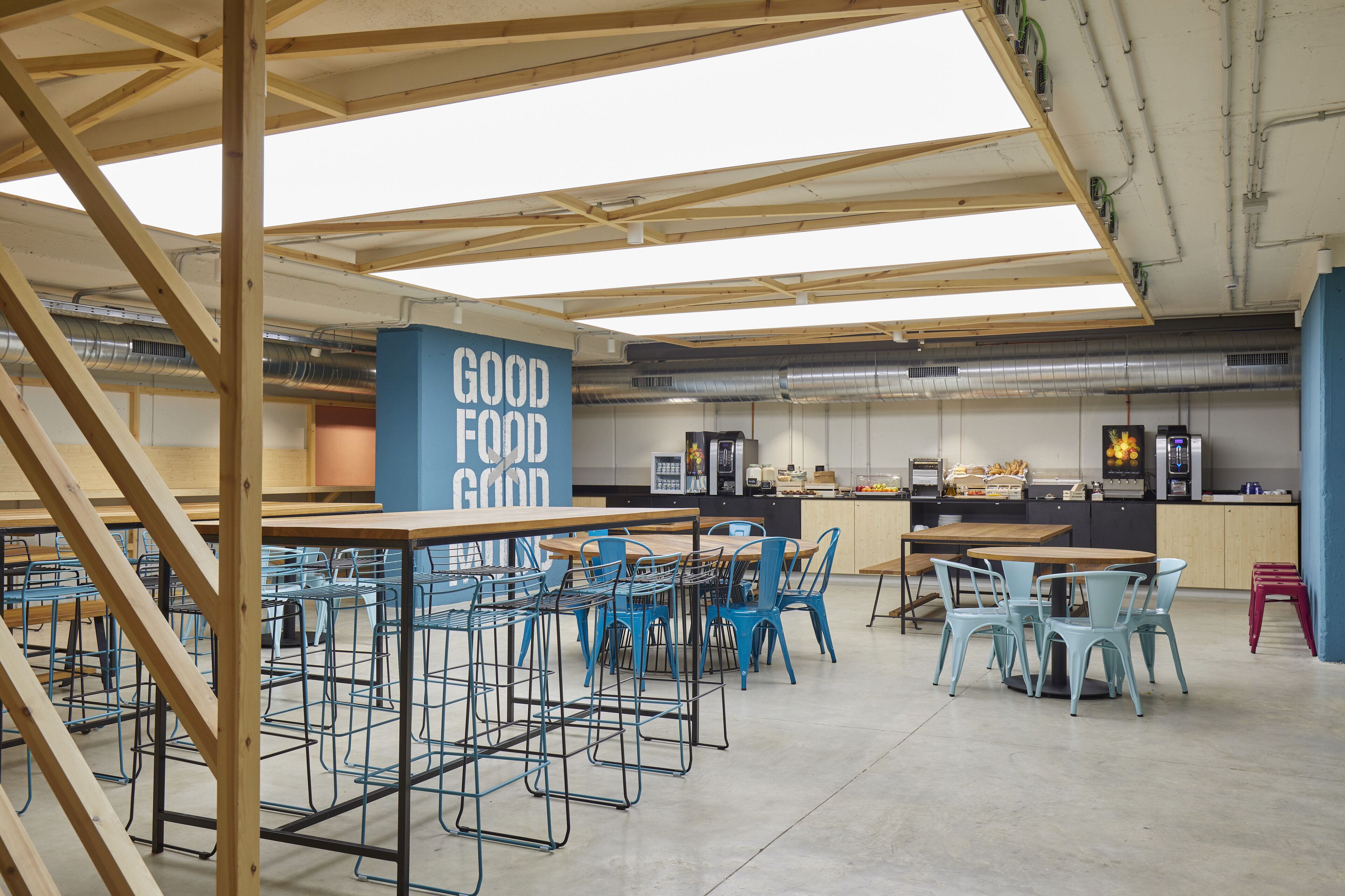 Eine moderne Küche mit Holzbalken, blauen Stühlen und einem Schild mit der Aufschrift 'GOOD FOOD'.