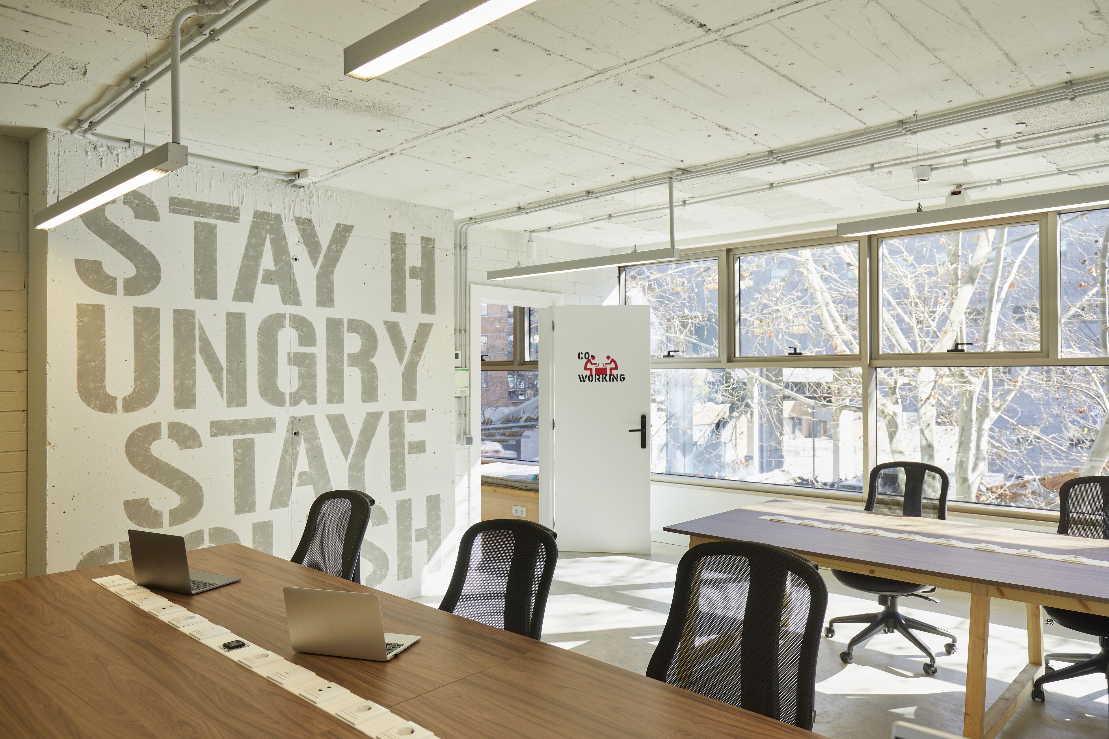 A conference room with a long table, several chairs, and a whiteboard with motivational text.