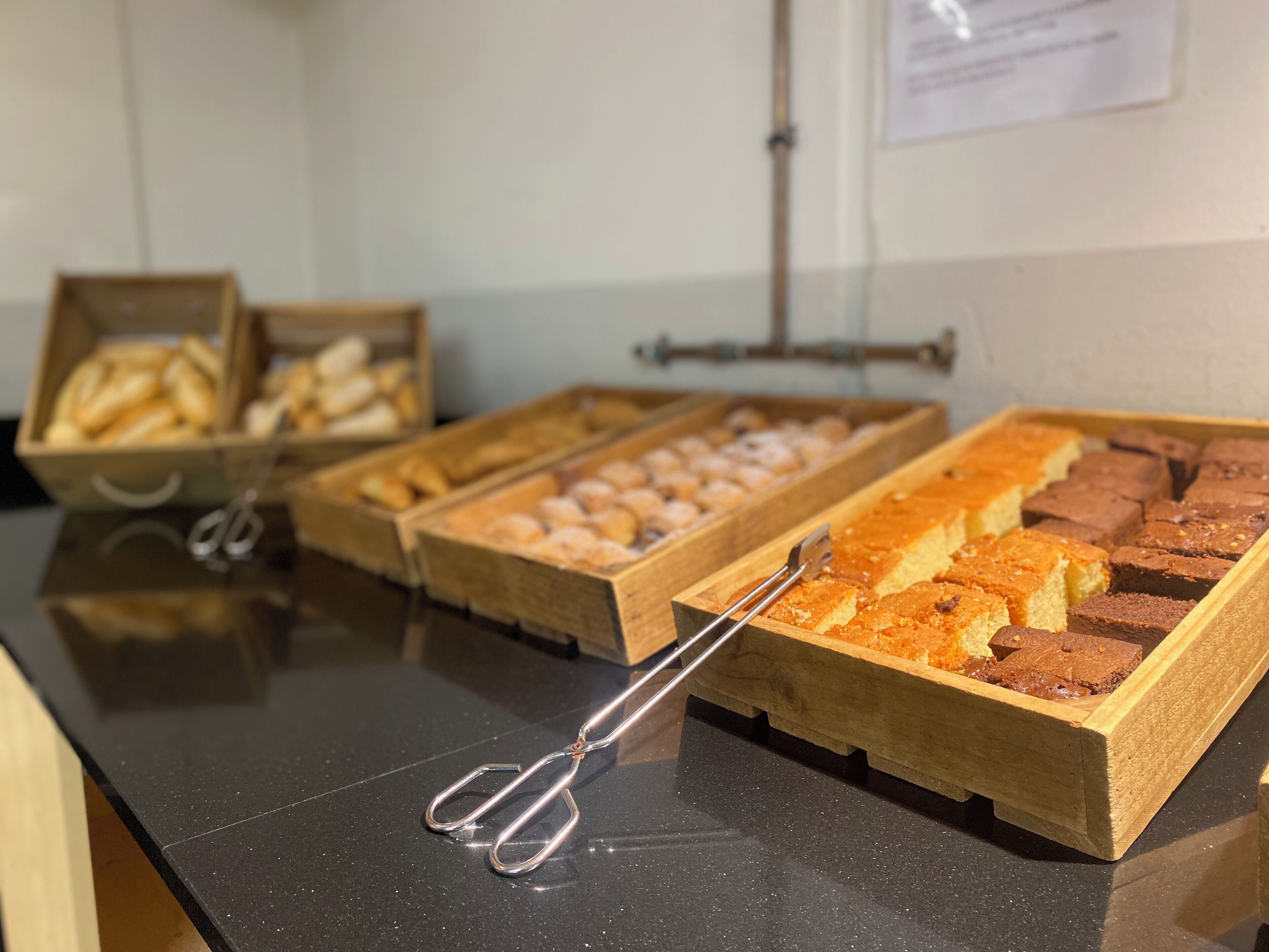 A buffet table with various baked goods in wooden trays, including bread and brownies.
