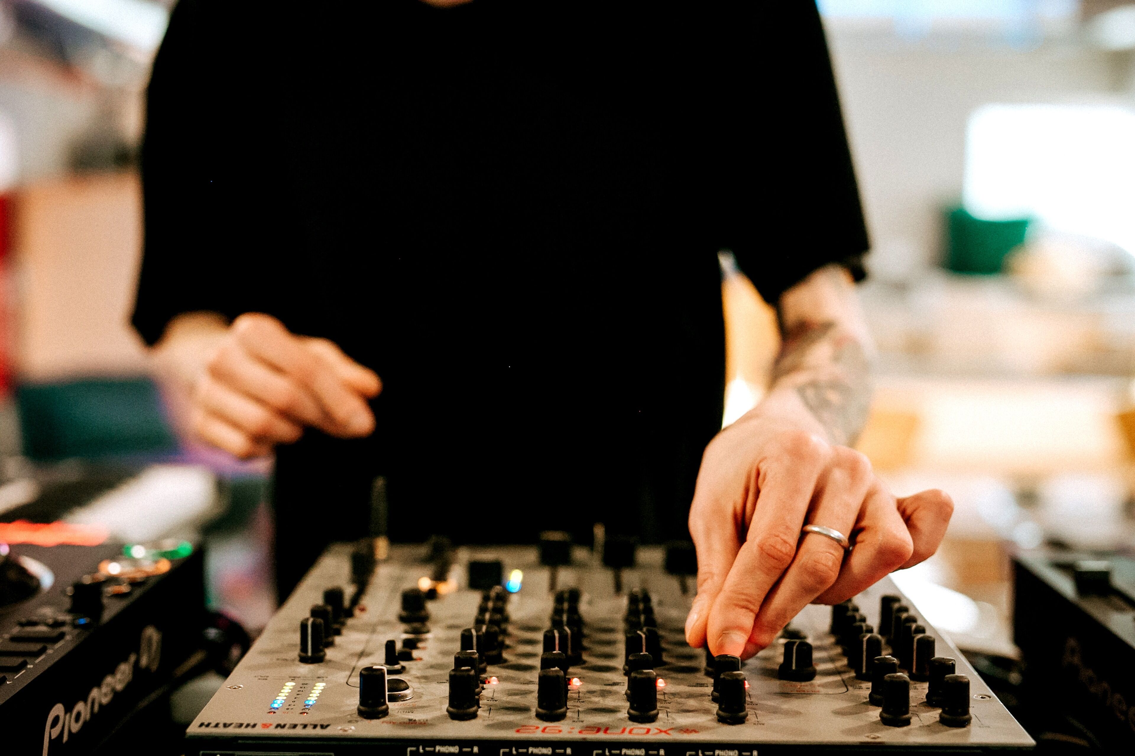 Une personne utilise une console de mixage audio Pioneer dotée de nombreux boutons et curseurs.