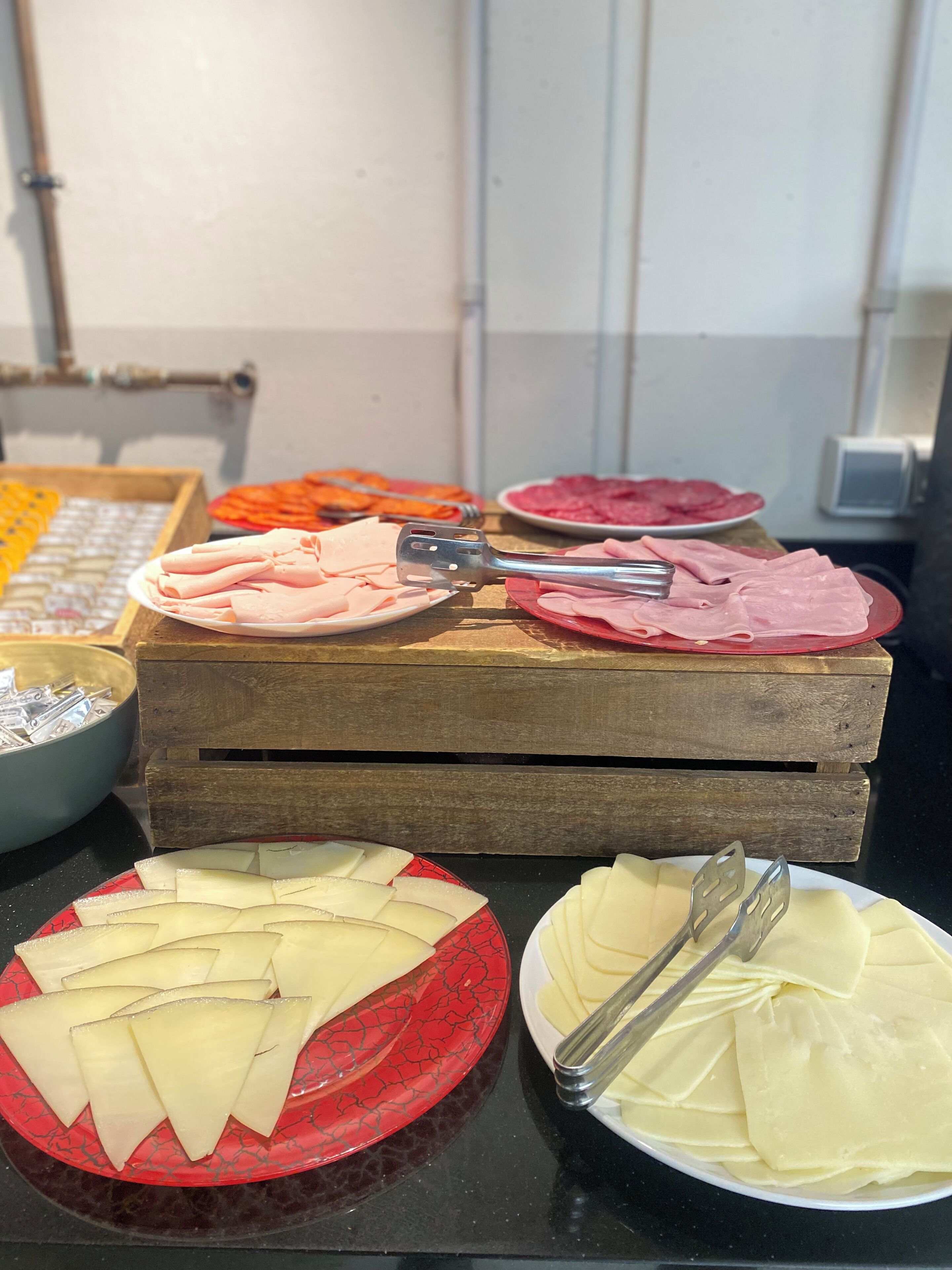 A buffet table with various food items, including sliced meats and cheeses, arranged on wooden boards and plates.