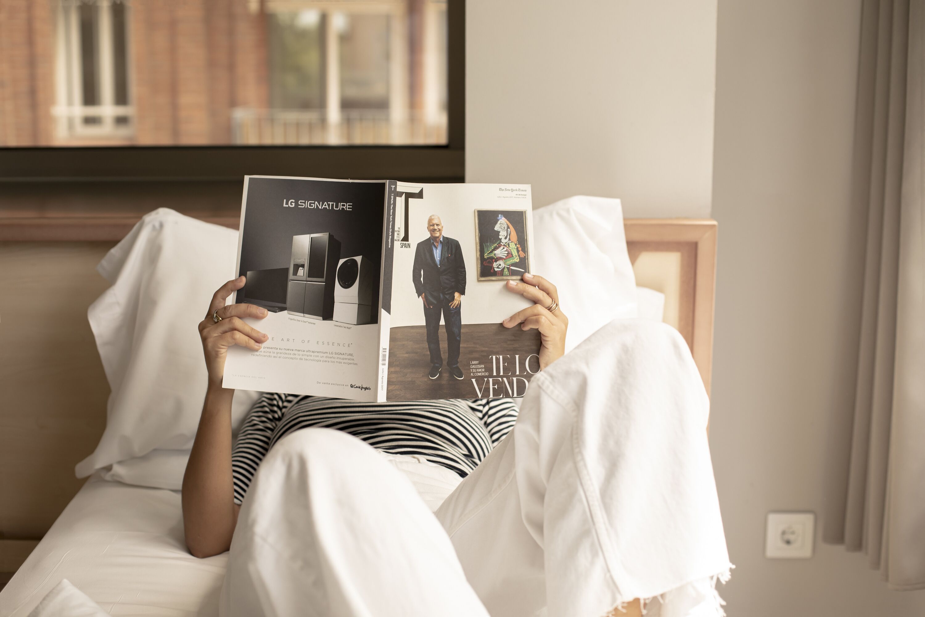 Una persona sdraiata su un letto che legge una rivista.
