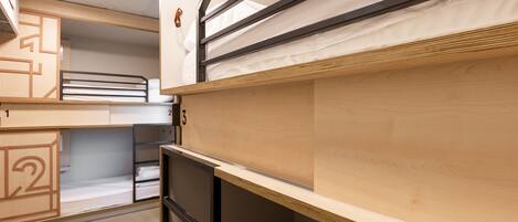 A bunk bed room with wooden bunk beds, numbered compartments, and a simple, functional design.
