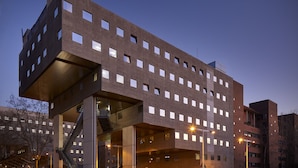 Un edificio moderno con varios pisos, amplias ventanas y una escalera destacada.