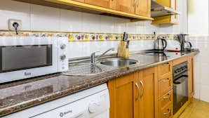 A kitchen with wooden cabinets, a white microwave, a sink, a toaster, and a dishwasher. - Magnifico apartamento en Marbella (Marbella)