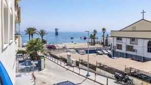 Vista costera con playa, una iglesia y un estacionamiento.