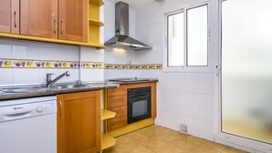 Une cuisine avec des meubles de rangement en bois, un lave-vaisselle, un four et une fenêtre à vitrage dépoli.