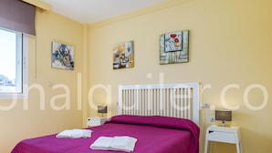 Quarto de hotel com uma cama, duas mesas de cabeceira e três quadros na parede.