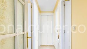 Um corredor com portas brancas e piso de azulejos.