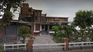 Et moderne hus i to etager med facade af mursten, en balkon og en indgang med låge.