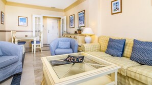 A living room with a glass coffee table, a sofa, a chair, and a dining area with a table and chairs. - Magnifico apartamento en Marbella con vistas al mar (Marbella)