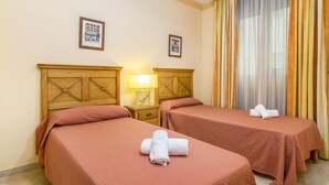 A hotel room with two single beds, a nightstand with a lamp, and a large window with curtains. - Magnifico apartamento en Marbella con vistas al mar (Marbella)