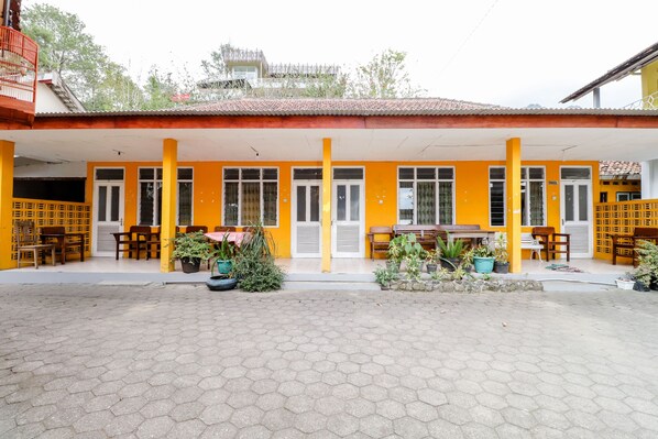 A building with yellow walls and a covered patio area with hexagonal tiles. - Wisma Joyo (Pakem)