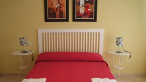 A hotel room with a bed, two side tables, and two framed artworks on the wall. - Frontal sea views penthouse (Marbella)