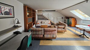 Un appartement moderne de style « loft » comprenant un lit en mezzanine, un escalier, un coin repas et un espace de travail.