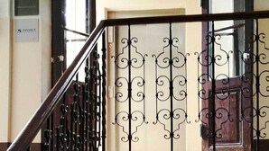 Un escalier avec une rampe en fer forgé menant à une porte ornée de panneaux de verre décoratifs.