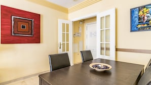 A conference room with a dark wooden table, two black chairs, a red and brown abstract painting, and a framed picture on the wall. - Magnifico apartamento en Marbella con vistas al mar (Marbella)