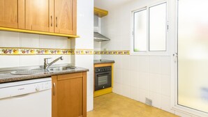 A kitchen with wooden cabinets, a Bosch dishwasher, a stove, and a window with a door. - Magnifico apartamento en Marbella con vistas al mar (Marbella)