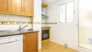 Una cocina con armarios de madera, un lavavajillas Bosch, una estufa y un ventanal con puerta.