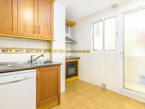 Una cocina con armarios de madera, un lavavajillas Bosch, una estufa y un ventanal con puerta.