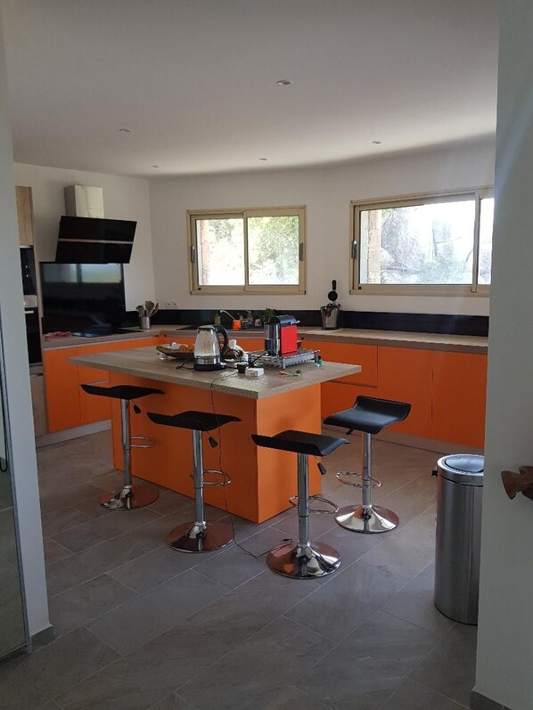 A modern kitchen with a central island, bar stools, and a stainless steel trash can. - Villa with pool in the heart of the rocks (Lecci)