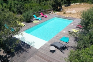 Relax by the pool surrounded by lush greenery and trees.