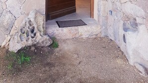 Una entrada de paredes de piedra con una puerta de madera, un escalón pequeño y un felpudo.