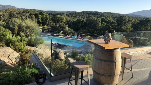 Zona junto a la piscina con vista despejada, sillas de descanso y un barril de madera.