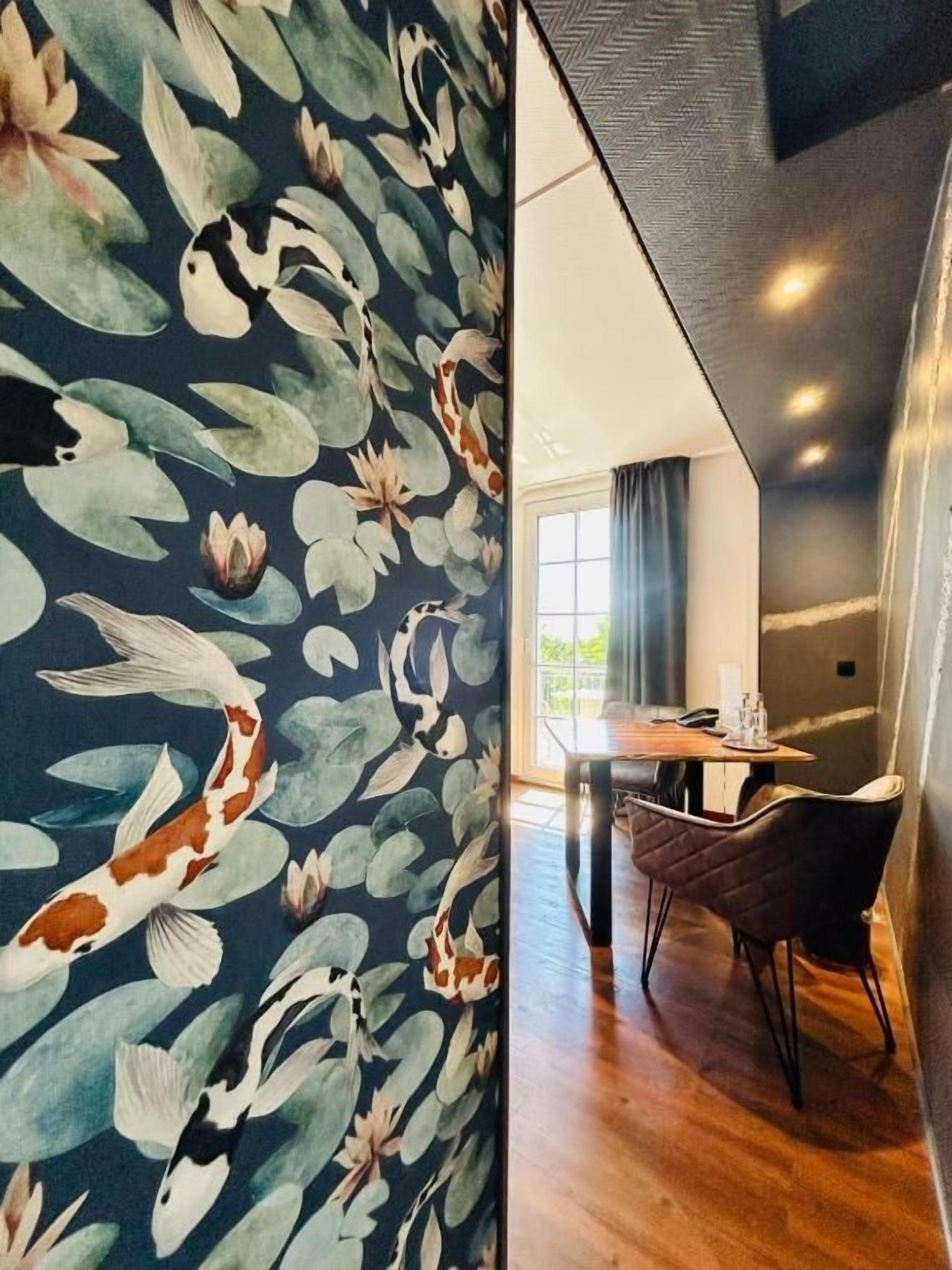 Una habitación con piso de madera, una mesa de comedor con sillas y un ventanal con cortinas.