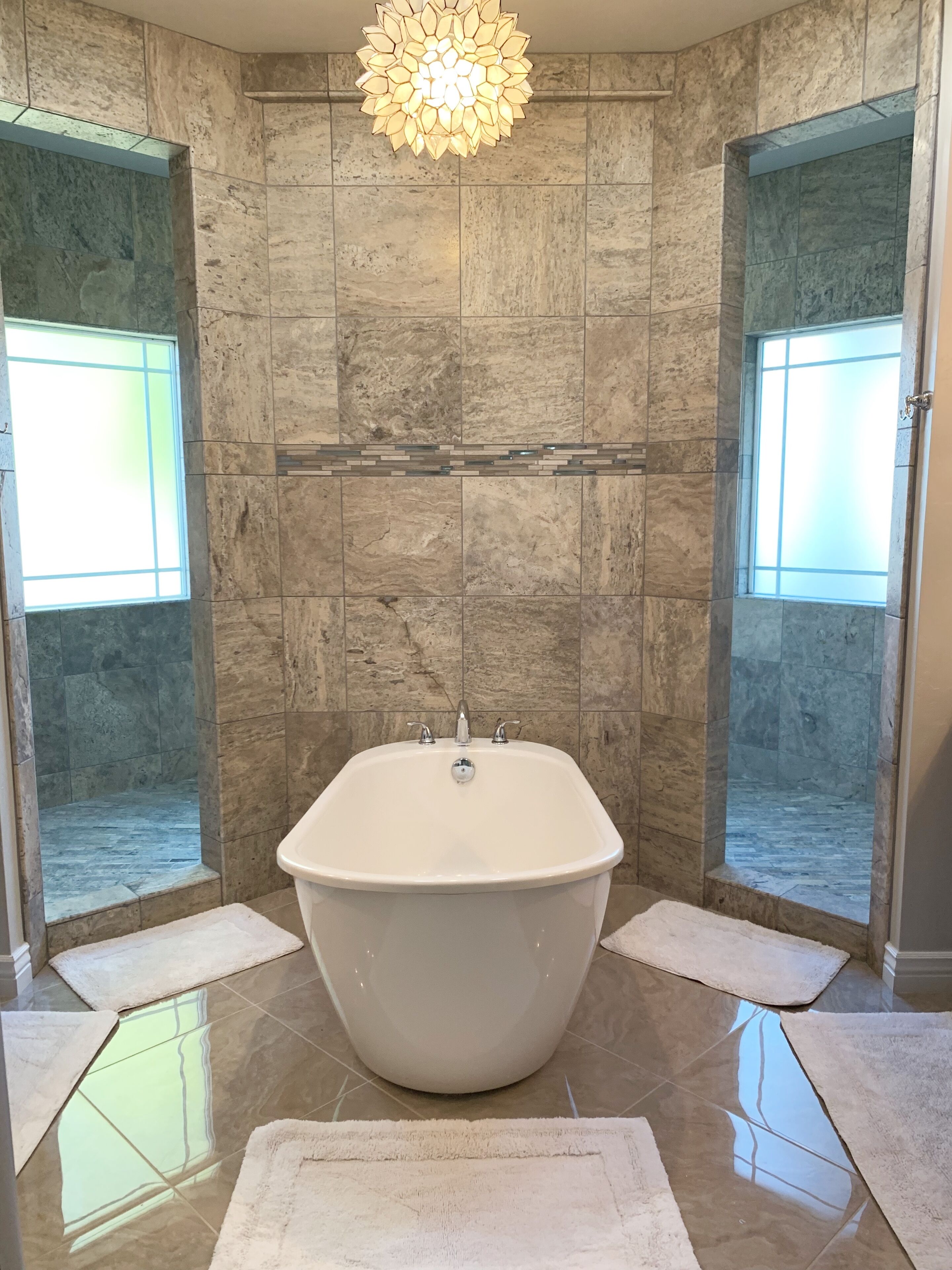 A bathroom with a freestanding bathtub, a shower enclosure, and a decorative light fixture.