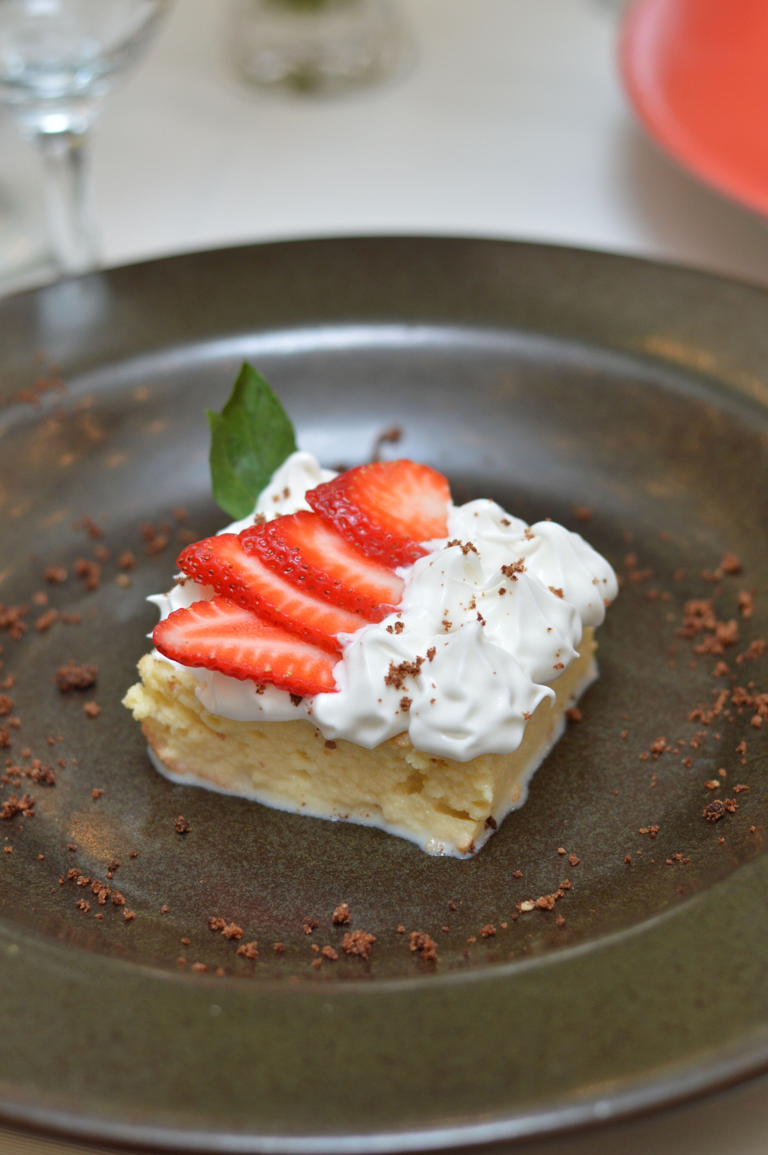 A dessert on a plate with strawberries and whipped cream.