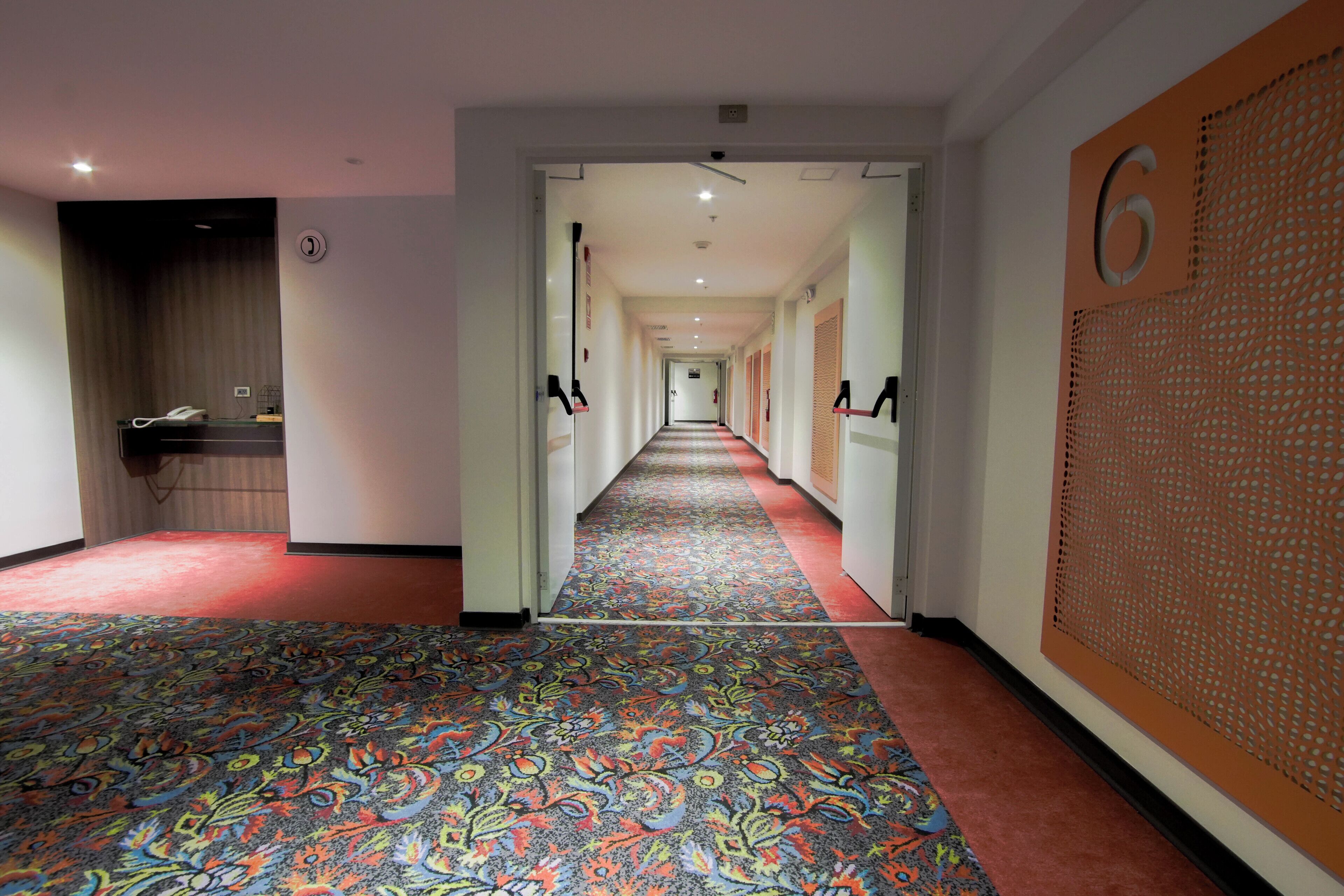 A hotel hallway with a patterned carpet, a number 6 sign, and a phone on a counter.