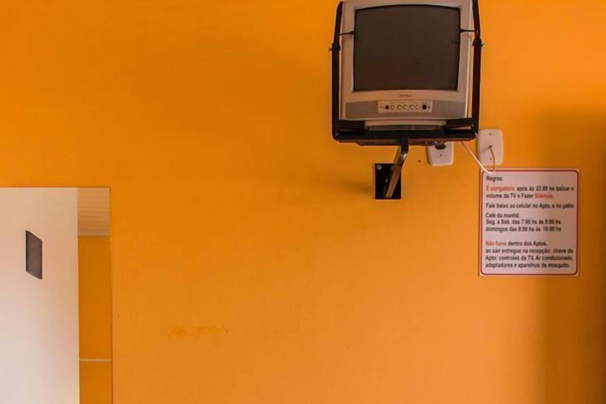 A hotel room with a bed, a chair, a small table, and a television mounted on the wall.
