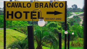 A sign for the Cavalo Branco Hotel with an arrow pointing right and a phone number (55)3257-2002. - Cavalo Branco Hotel (São Vicente do Sul)