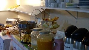 A buffet table with various food items and labeled containers, likely for beverages. - Cavalo Branco Hotel (São Vicente do Sul)