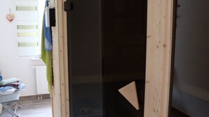 A wooden-framed sliding door with a black glass panel, a white radiator, and a window with blinds. - Cottage on the forest with sauna (Bad Elster)