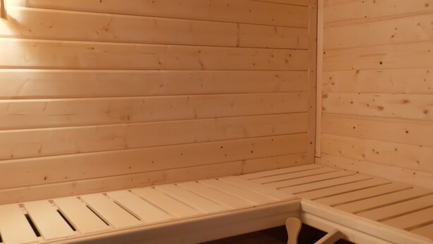 A sauna with wooden benches and a bucket. - Cottage on the forest with sauna (Bad Elster)