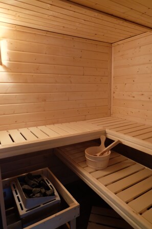 A sauna with wooden benches and a bucket. - Cottage on the forest with sauna (Bad Elster)