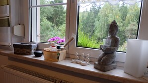 A window with a statue of Buddha, a Buddha figurine, and a small Buddha statue on a shelf. - Cottage on the forest with sauna (Bad Elster)