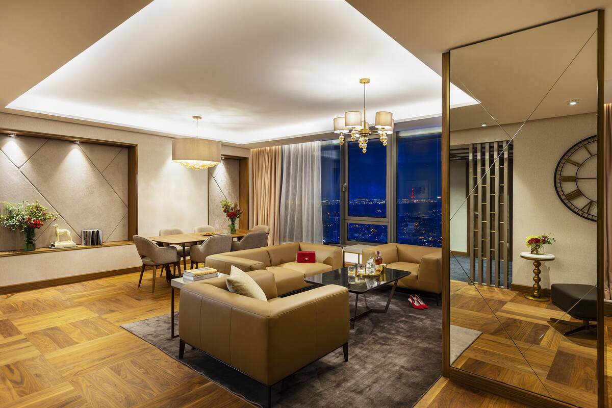 Un salon moderne avec un canapé, une table basse et une vue sur la ville la nuit.