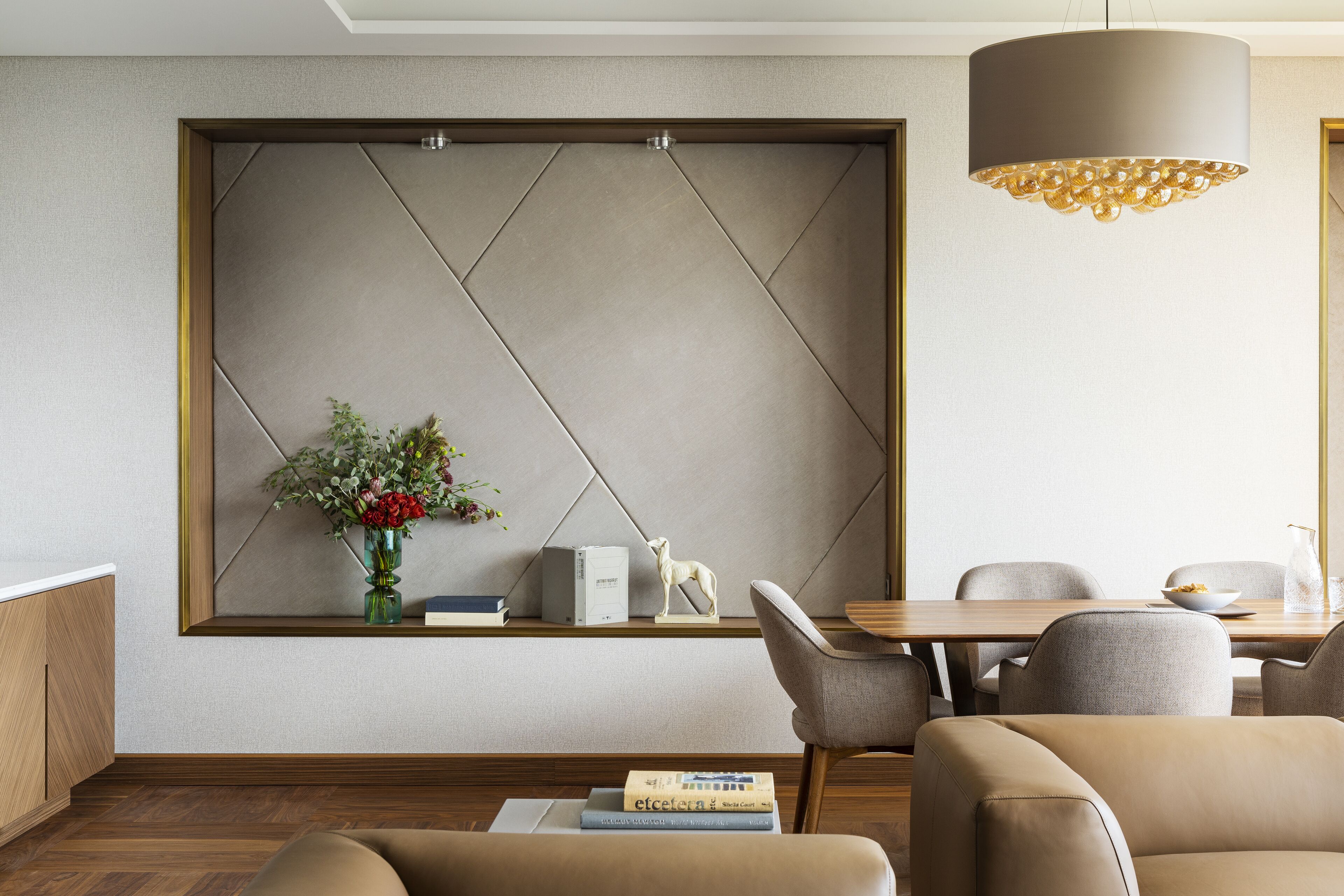 A modern hotel room with a large window, a wooden dining table, and comfortable seating.