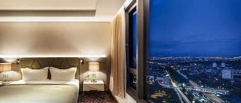 Ein Hotelzimmer mit einem großen Bett, einem Nachttisch mit Lampe und Blick auf nächtliche Stadtansicht.