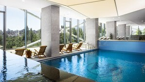 An indoor swimming pool with clear views of the cityscape through large windows.
