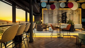 A modern dining area with a view of the sunset, featuring a mix of seating arrangements and a brick wall backdrop.
