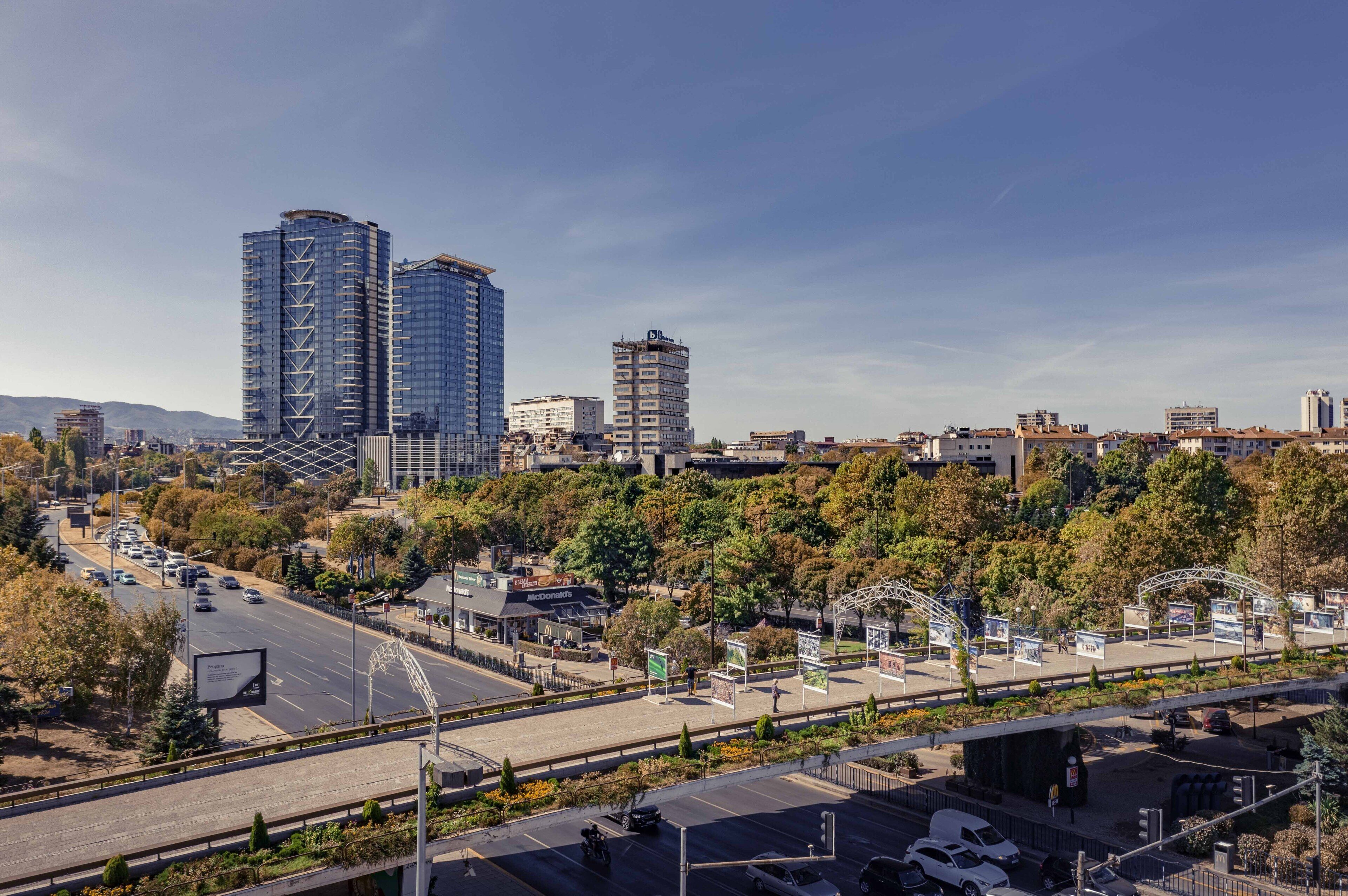A cityscape with modern high-rise buildings, a highway, and a McDonald's restaurant.